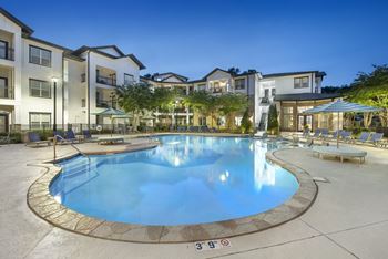 A swimming pool surrounded by apartment buildings at dusk.